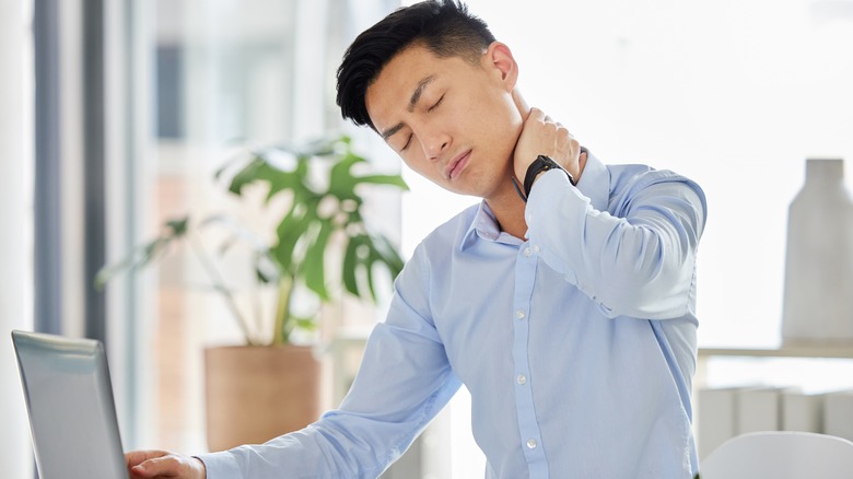 man with sore neck using laptop