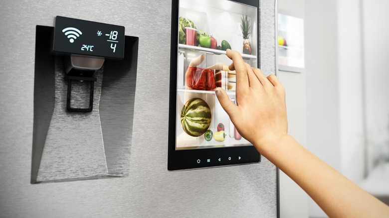 A person interacting with a smart fridge's display.