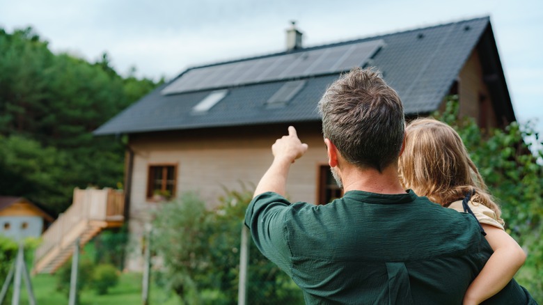 family in front of house with solar panels on roof