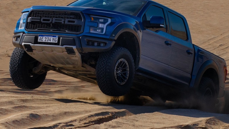 Blue Ford Raptor driving in sand