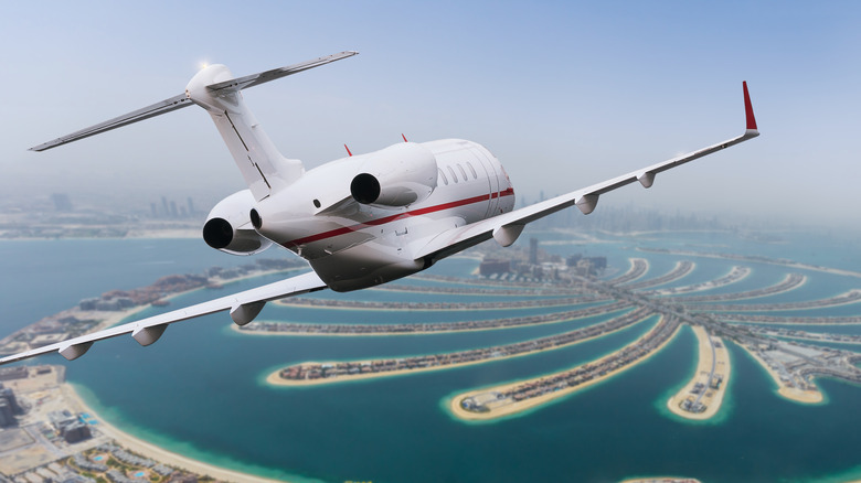 Private jet flying over palm islands