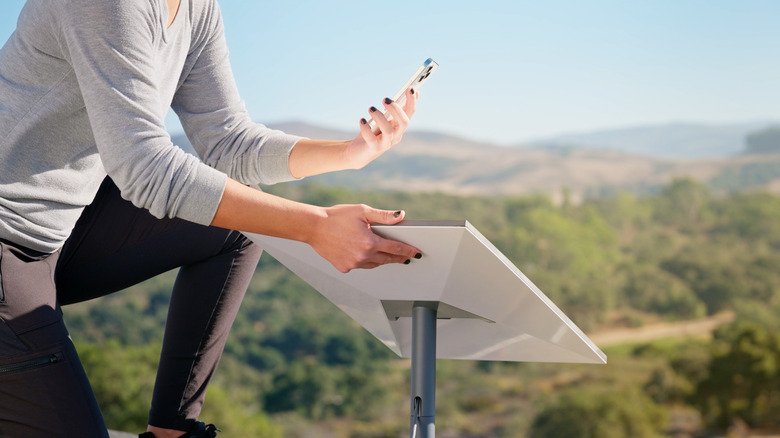 Woman aligning Starlink dish while holding phone