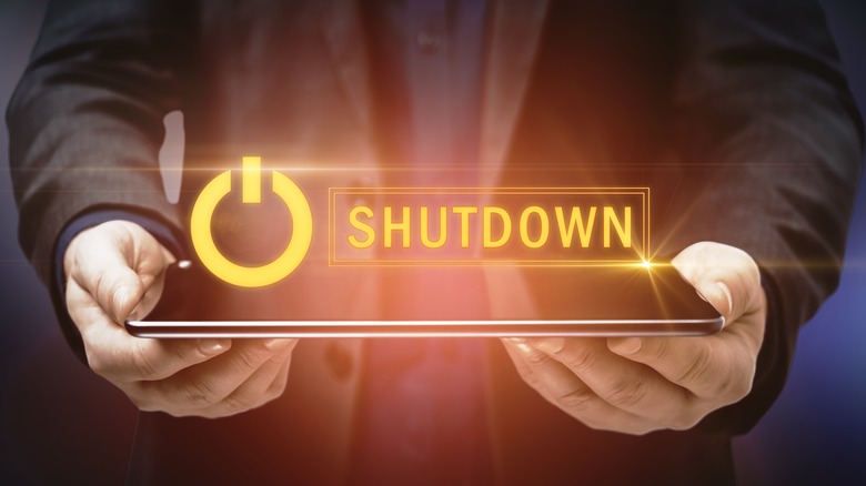 Shutdown glowing over person holding tablet