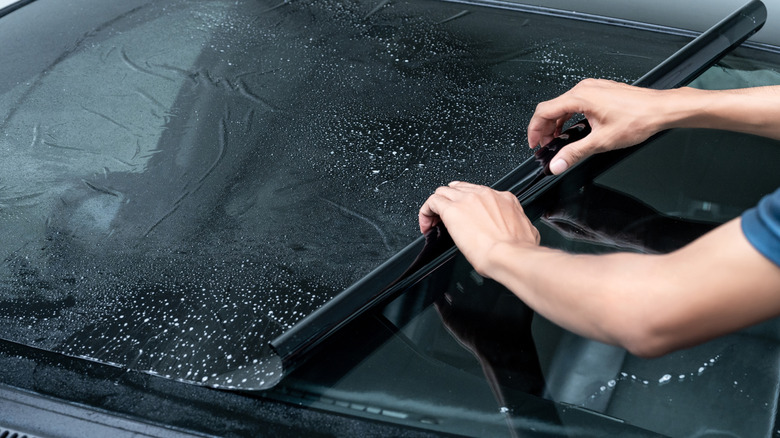 A person applying window tint to a car window