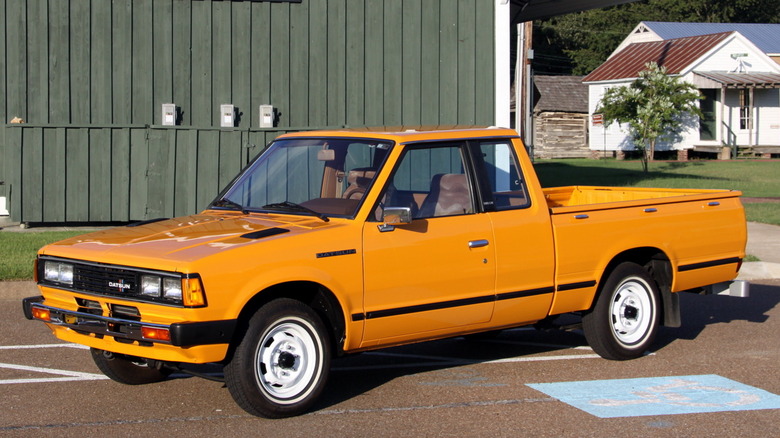 Orange Datsun mini truck parked in front of a building