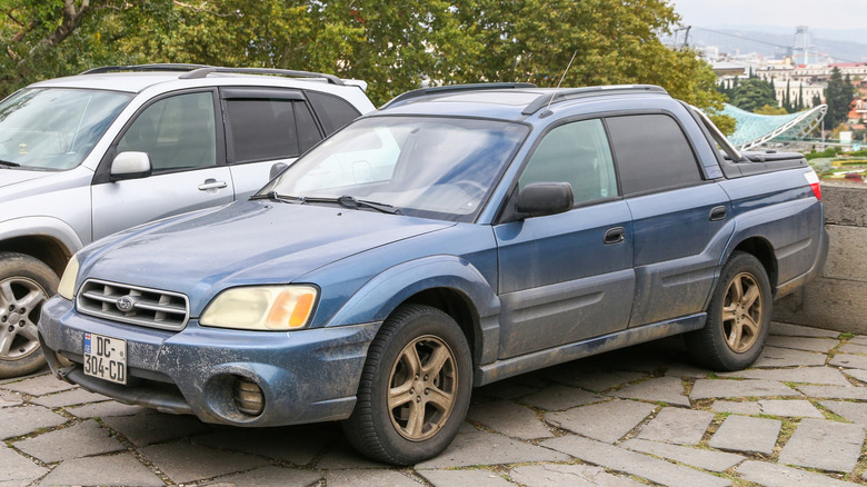 Muddy blue Subaru Baja parked