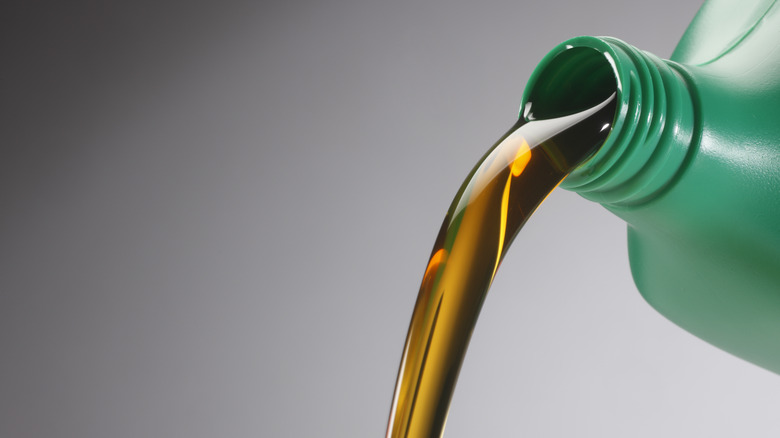 Pouring engine oil from green bottle