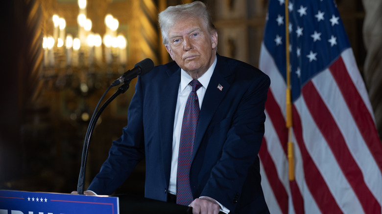 Donald Trump standing on a stage with a stern look on his face.