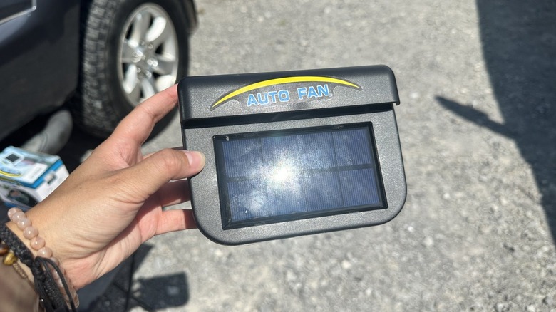 Auto Fan in hand with sun directed on solar panel