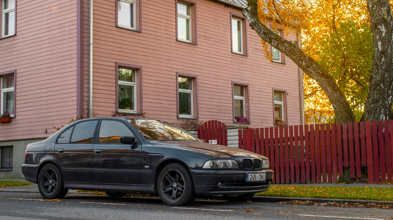 A black E39 BMW 5 Series parked on the street, front 3/4 view