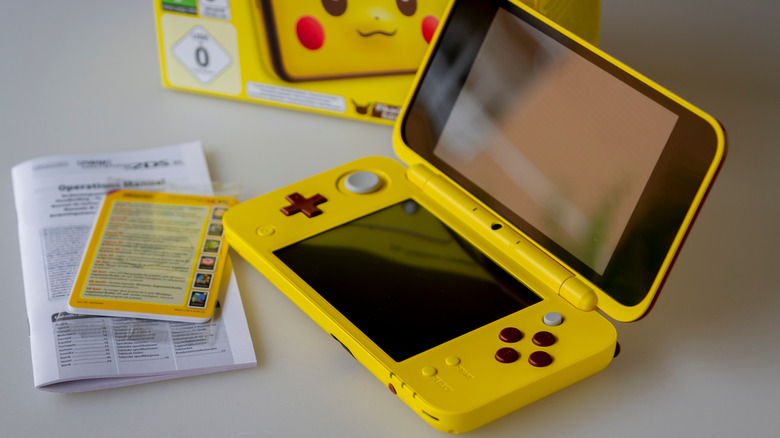 A yellow Pikachu themed Nintendo DS with instruction manual