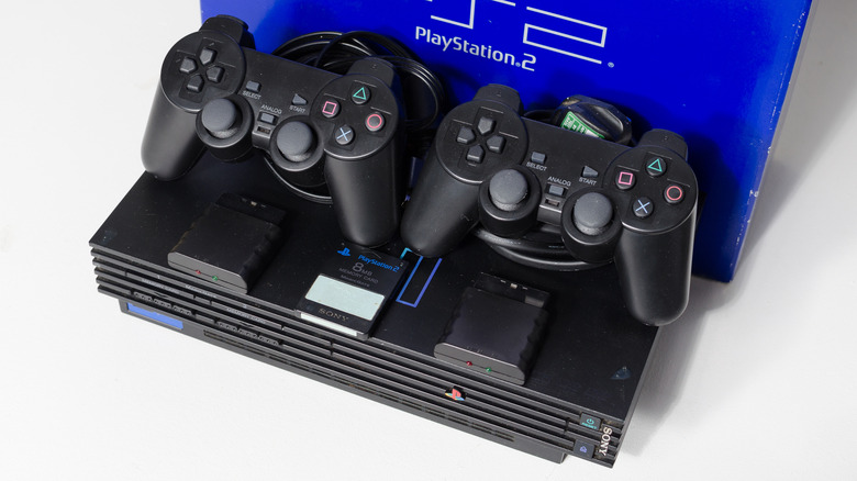 A black PlayStation 2 controllers and a memory card