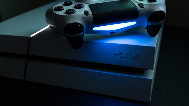 A PlayStation 4 with a controller on top in the dark