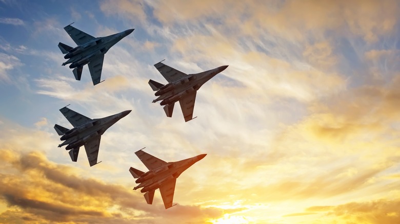 4 fighter jets flying in sunset