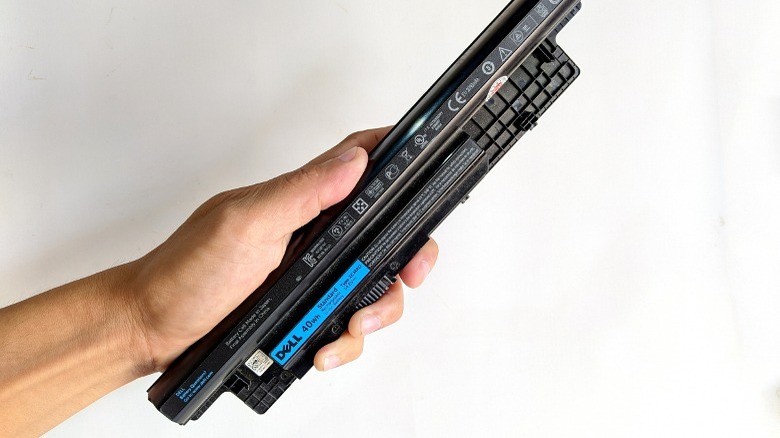 A hand holds Dell laptop batteries