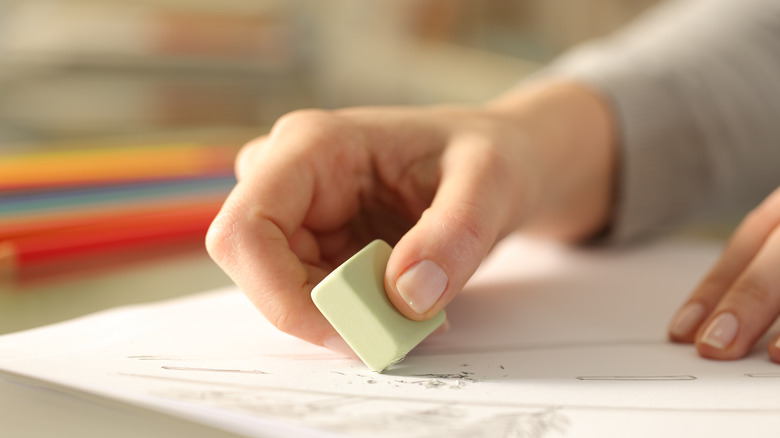 Hand using an eraser on paper