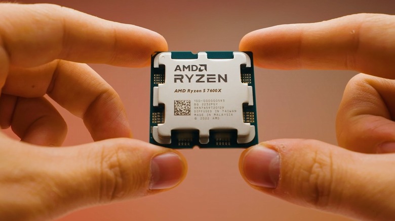 Hands holding AMD Ryzen 5 7600X CPU