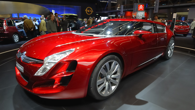 The Citroen C-Metisse at an auto show floor in red, front 3/4 view