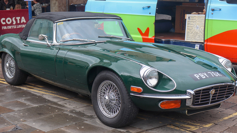 A green 1972 Jaguar Series 3 by a van