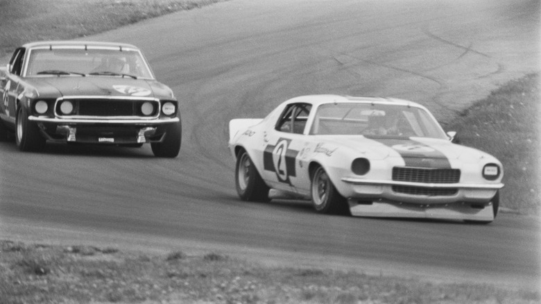 A black and white image of two cars racing in the 1970s