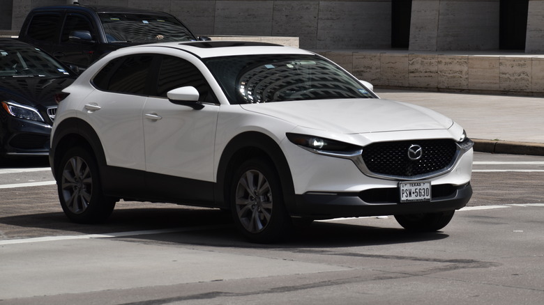 A white Mazda CX-5 driving through city traffic