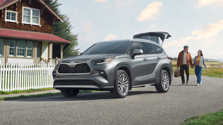 A gray Toyota Highlander in front of a red house