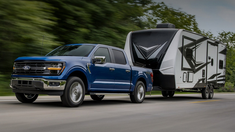 A blue Ford F-150 pulling an RV on a highway