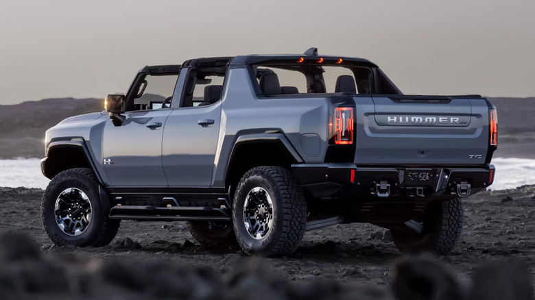 A shale blue GMC Hummer EV driving in a rocky area