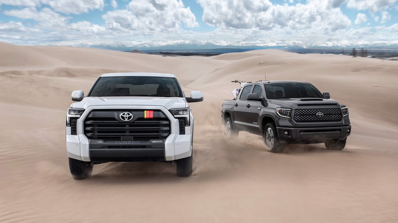 Two Toyota Tundra trucks driving along sand dunes