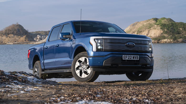 A blue Ford F-150 Lightning by a lake