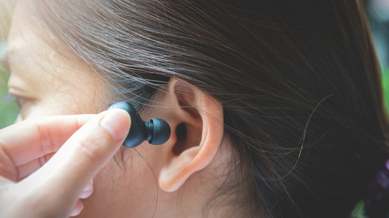 woman inserting right earbud
