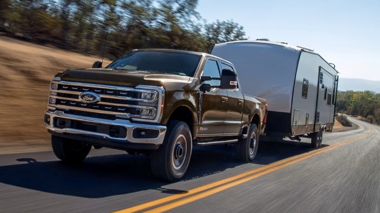 Darkened Bronze Ford Super Duty F-250 towing camper with trees in the background