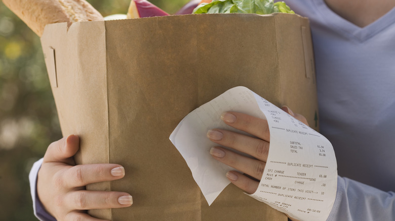 holding grocery bag and receipt