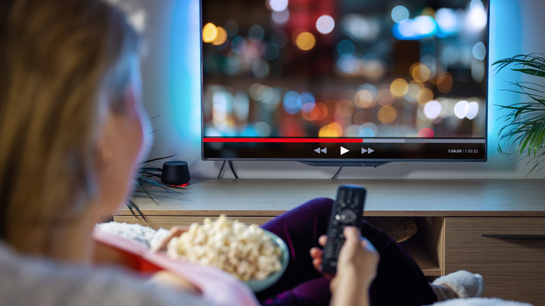 woman watching TV while eating popcorn