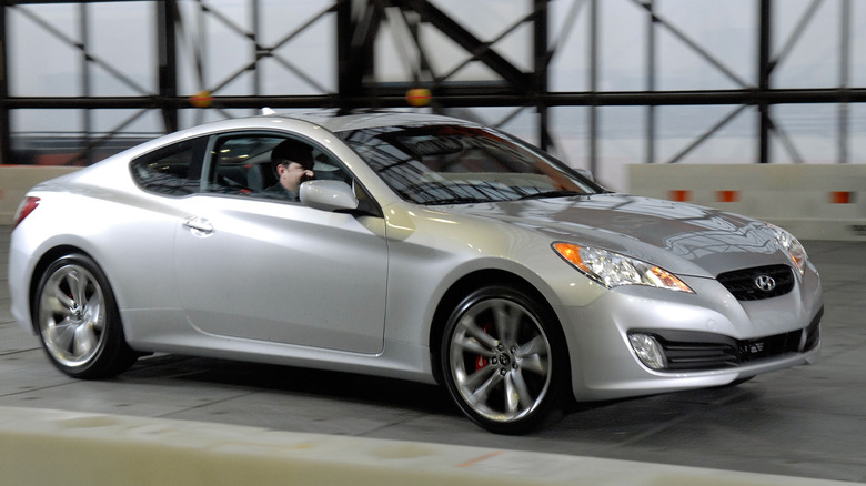 A Hyundai Genesis Coupe in silver being driven hard, front 3/4 view