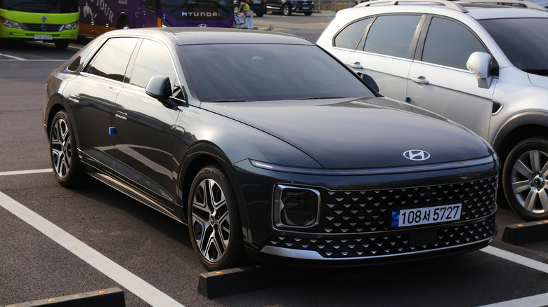 A black Hyundai Grandeur in a parking spot, front 3/4 view