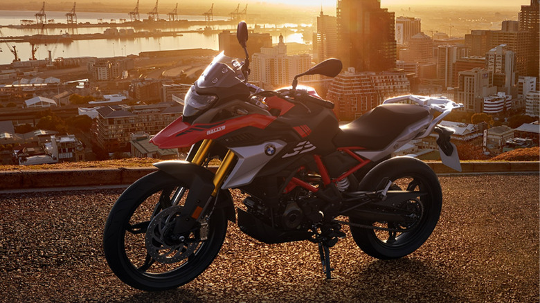 A red BMW motorcycle against a cityscape at sunset