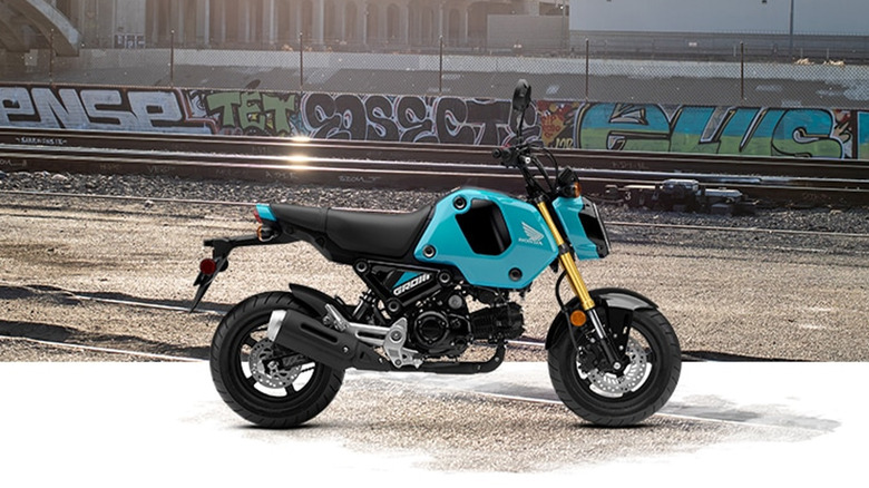 A blue Honda Grom next to train tracks