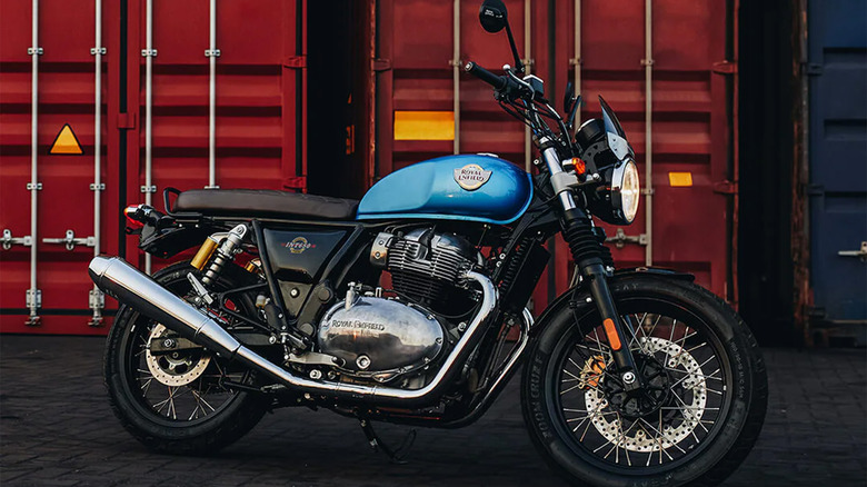 A blue Royal Enfield near some shipping containers