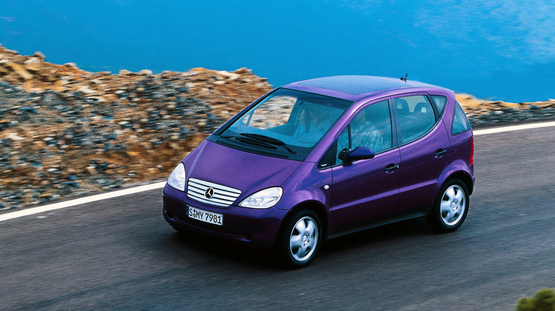 First-gen Mercedes-Benz A-Class driving at speed on a road near a water surface front 3/4 view