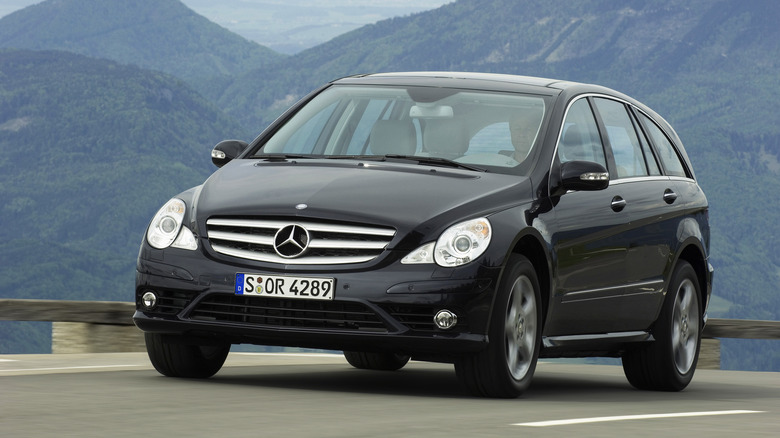 Mercedes-Benz R-Class prefacelift model driving at speed on an open road with mountains in the background