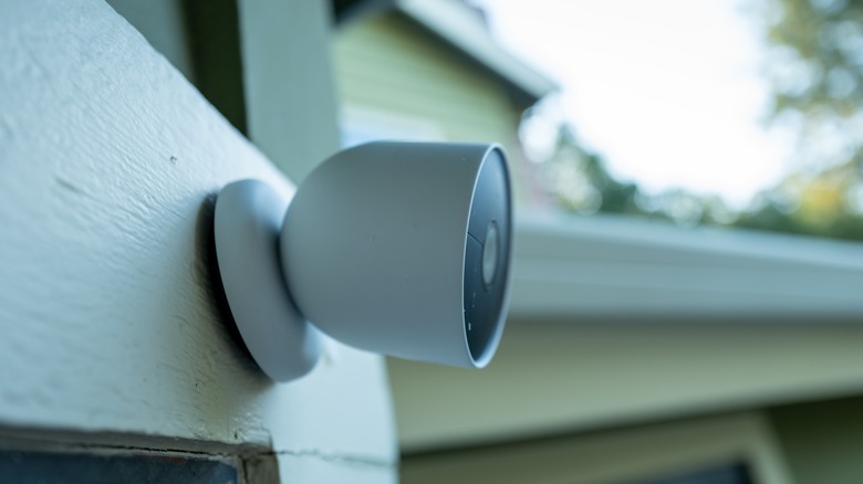 White outdoor camera mounted on wood siding