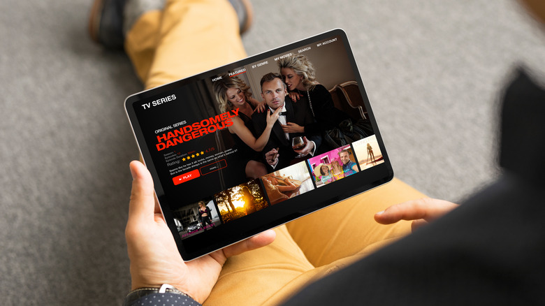 Person holding tablet browsing Netflix.