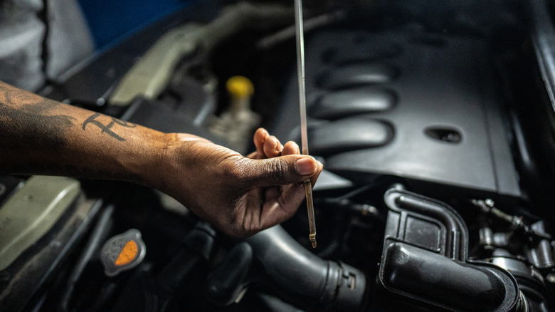 Mechanic checking oil with dipstick