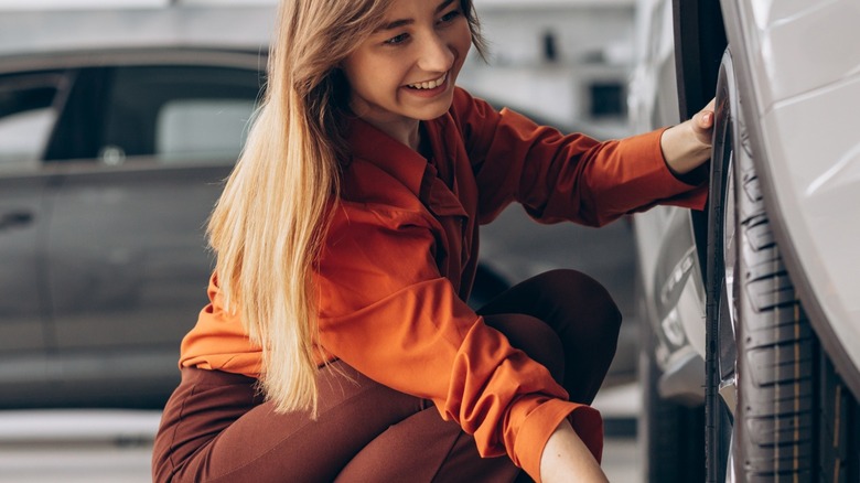 woman checking out the tires on a car