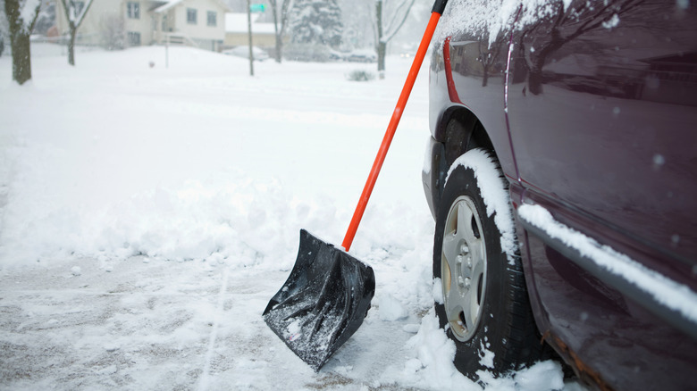 snow shovel leaning on car