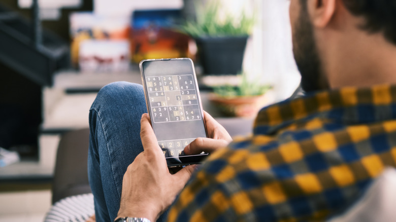 Man playing Sudoku on phone