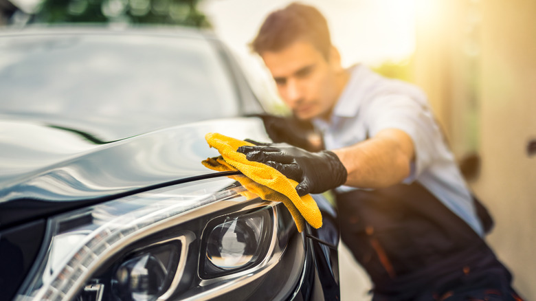 Man detailing car with rag