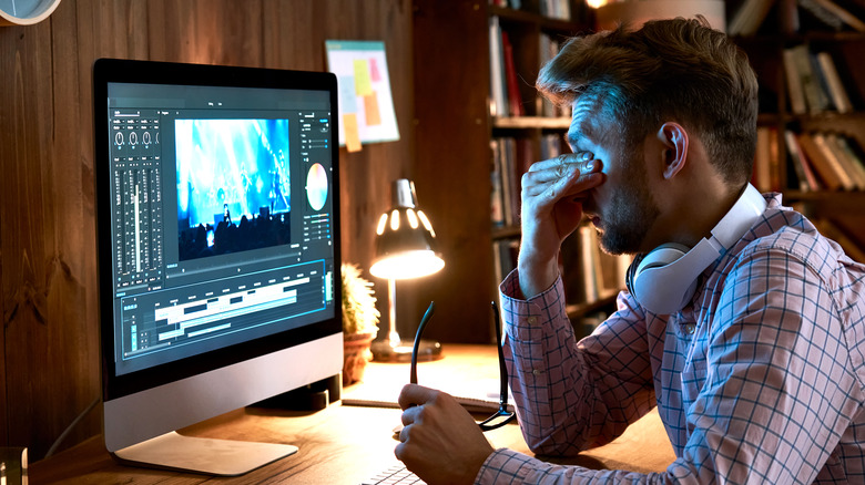 Tired man at computer rubbing eyes