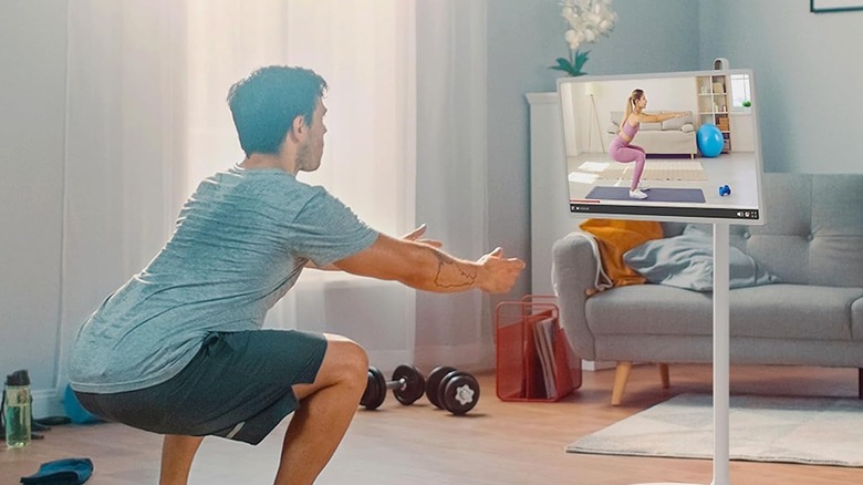 A man doing physical exercise in front of a LG StanbyME, which is playing a workout video